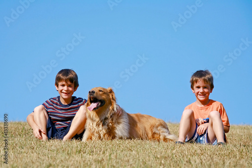 Boys and Dog Sitting on the Side of a Hill