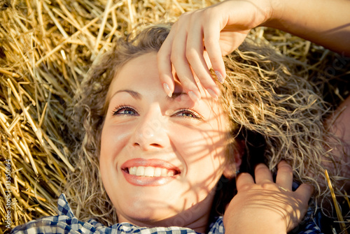 Beautiful country girl lying and smile on the haystack