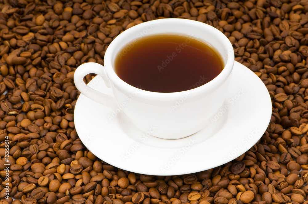 White cup on the background of coffee beans White cup on the background of coffee beans