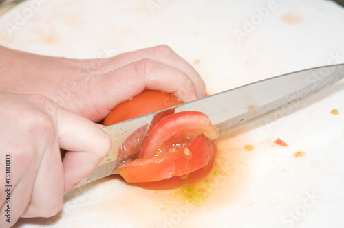 A knife blade slices trough a tomato