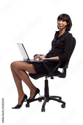 Laughing brunette woman sitting in the chair and holding laptop