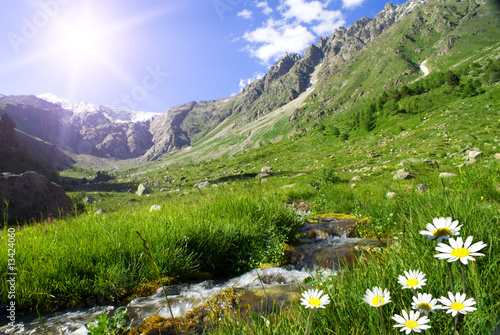 Mountain landscape with the small river, sun and colors