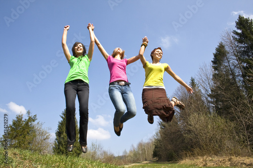 happy girls jumping on meadow