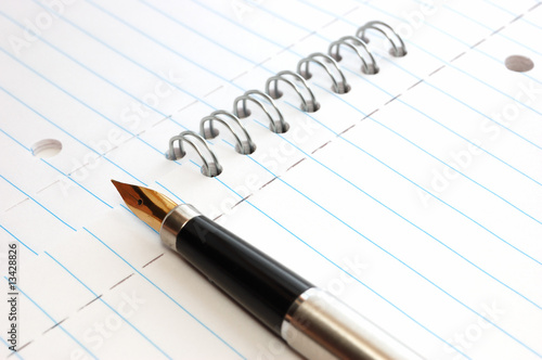 A gold pen on a spiral-bound notepad