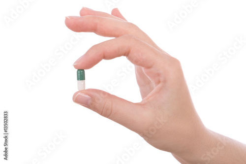 Hand holding a capsule or pill isolated on white. photo