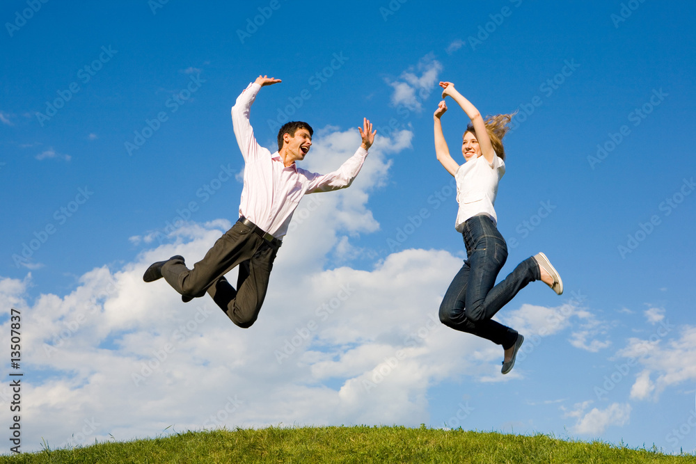 Happy smiling couple jumping in blue sky Happy smiling couple jumping in blue sky