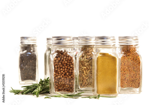 Spice jars with fresh rosemary leaves against white