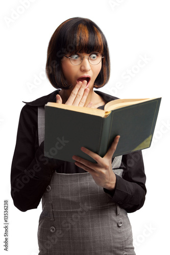 Surprised brunette schoolgirl looking in the book