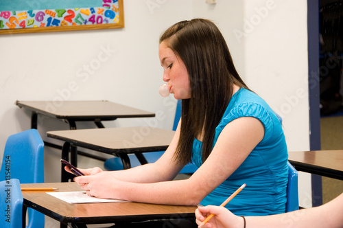 girl blowing bubble and texting in class