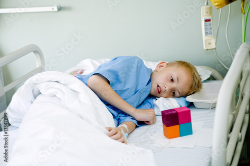 Sick boy in hospital bed looking at his toy