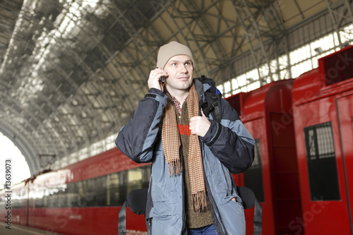 Photography Man with backpack andm mobile phone at the train station