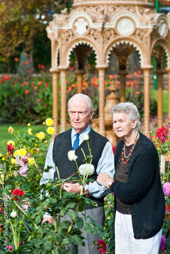 Senior couple admiring dahlias near ornate drinkingfountain