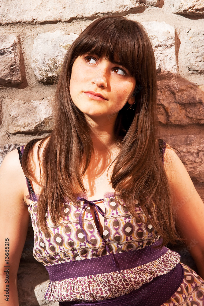 Fototapeta premium Beautiful girl standing near wall