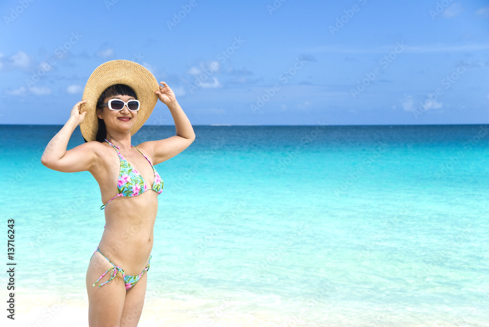 Woman with Straw Hat and String Bikini Standing on a Beach