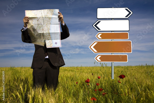 businessman lost in field using a map - sign direction