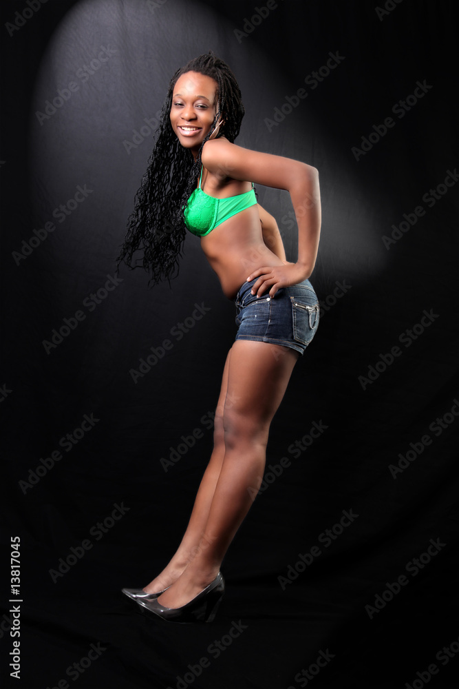 young afro-american woman in bra and shorts against black backgr young afro-american woman in bra and shorts against black backgr
