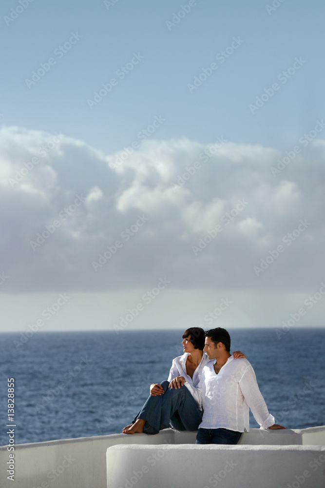 couple assis sur un mur face à la mer