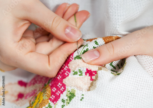 Woman hands doing cross-stitch. A close up of  embroidery.