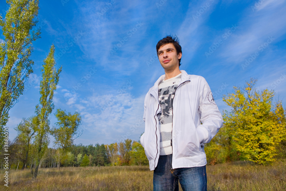 Smiling young man against background of sky and trees
