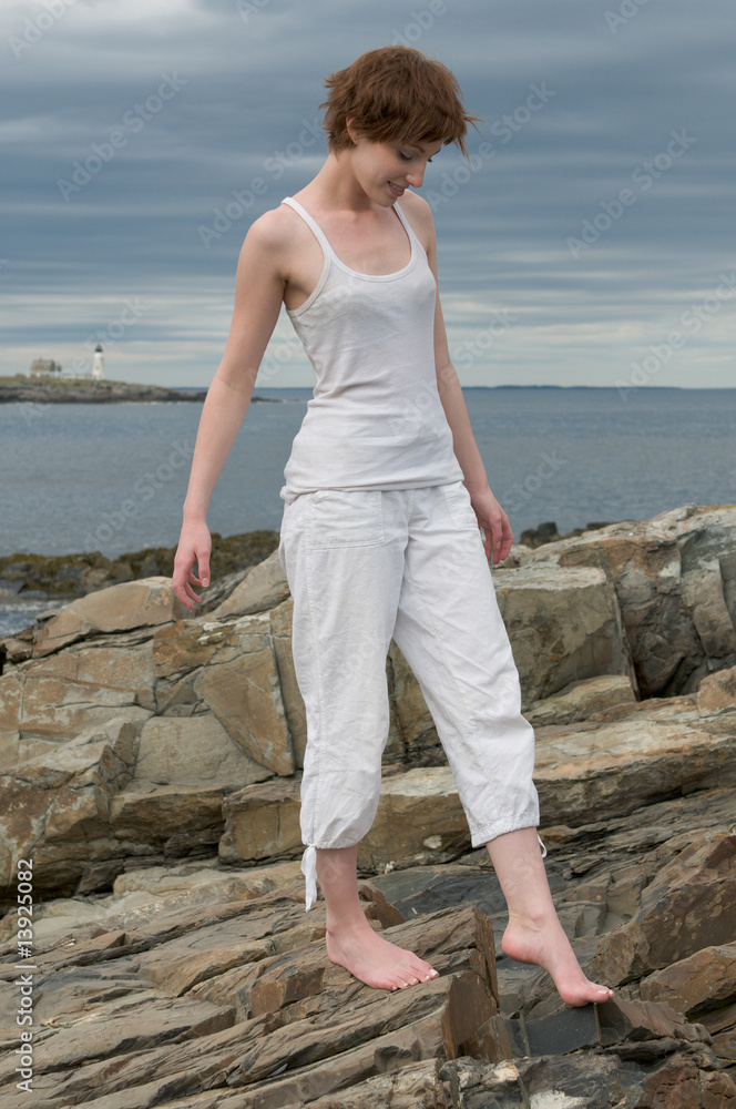 Beautiful young woman walking on a rocky beach Beautiful young woman walking on a rocky beach