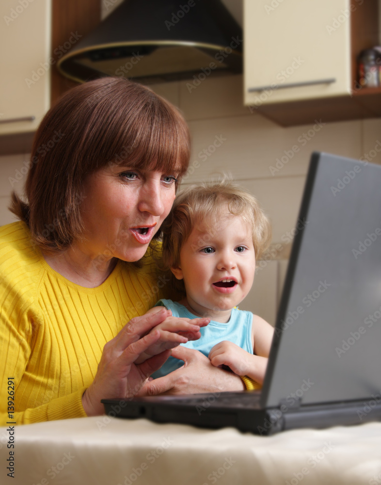 Baby and grandmother with astonishment look in the laptop Baby and grandmother with astonishment look in the laptop