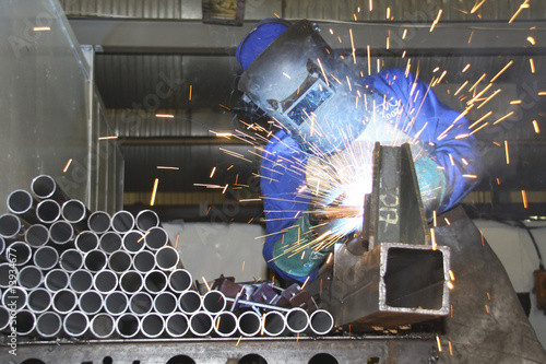 Man welding pipes on a production line