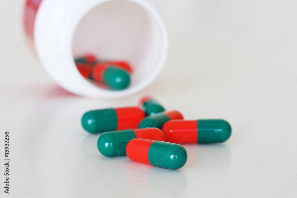 A overturned pill bottle with spilled capsules. A overturned pill bottle with spilled capsules.