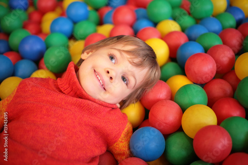 little girl lies on multi-coloured plastic spheres