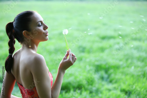 Cute young woman is blowing into blow ball