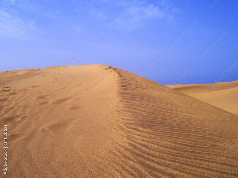 Sand dune detail against blue sky and white clouds