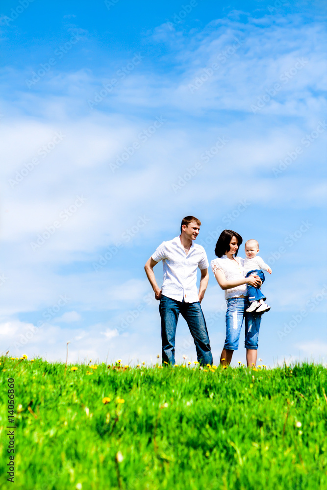 Happy young family on green grass over sky Happy young family on green grass over sky
