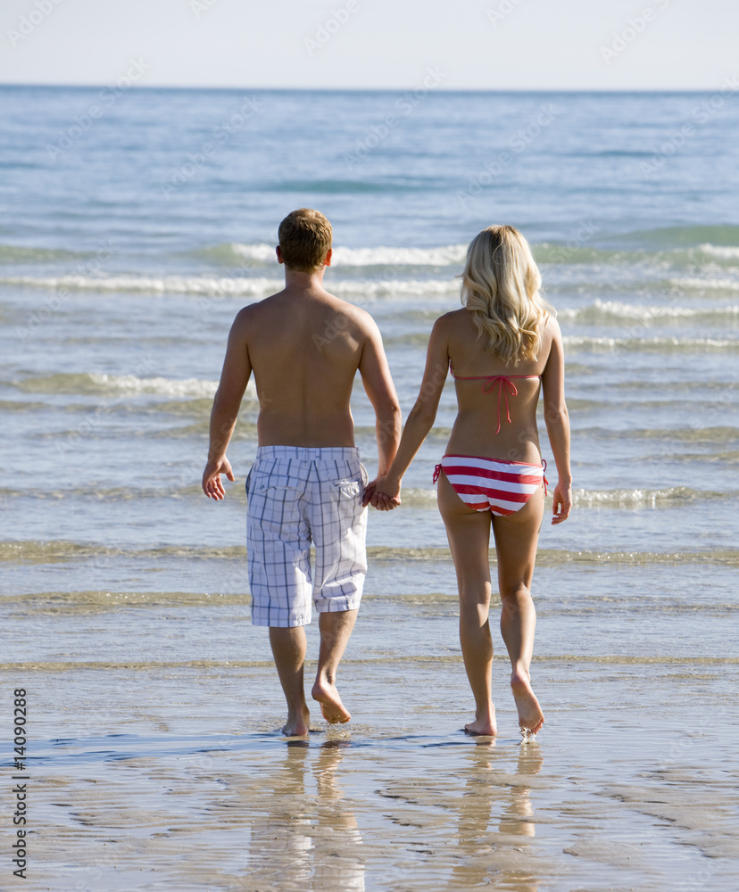 A young couple holding hands on the beach