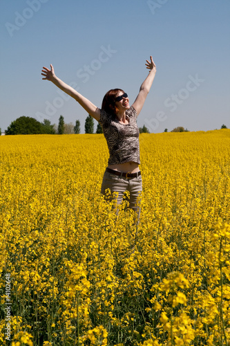 Happy woman in the field of blossoming yellow flowers