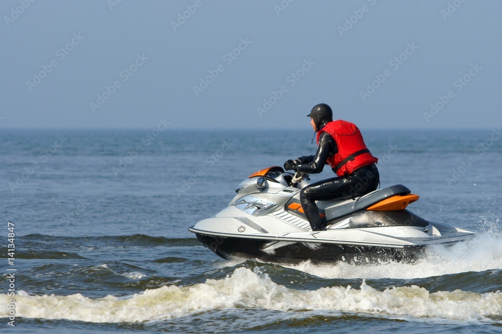 Jet ski in action with water spray on the blue sea