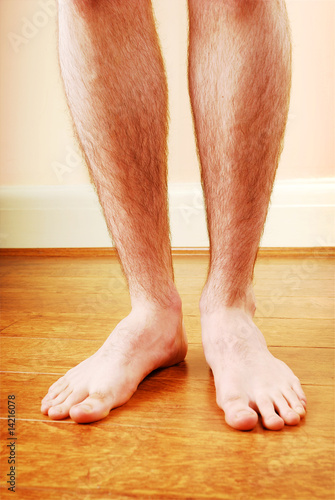 A man's naked legs standing on wooden floor