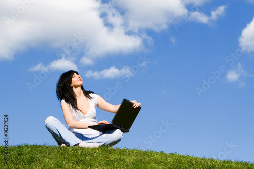 pretty woman with laptop on the green grass