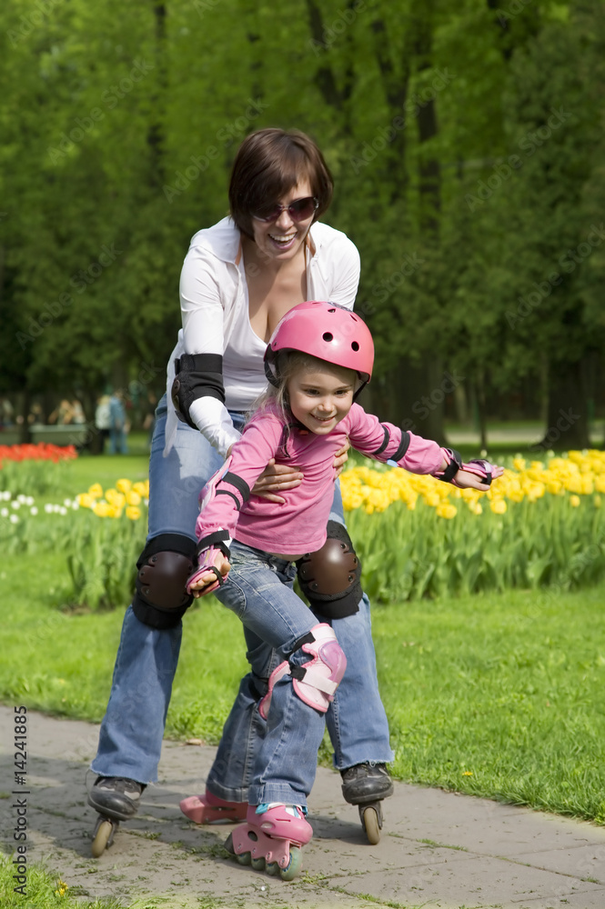 Fototapeta premium Mother with daughter ride rollerblades. Focus on a child
