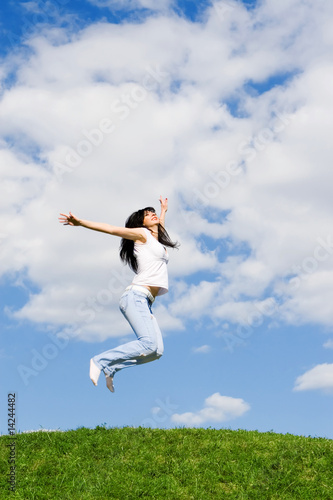 pretty young woman is jumping on green grass