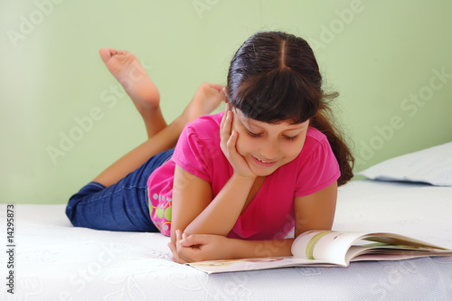 Niña leyendo libro en la cama