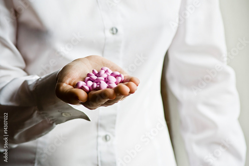A doctor holding a handful of vitamin supplement capsules