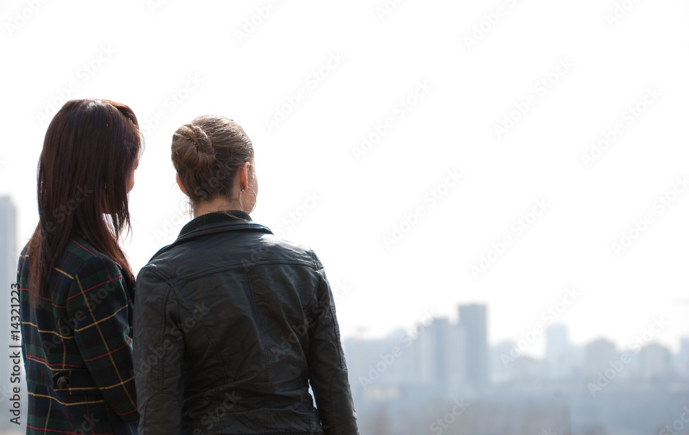 Two girls looking to a city panorama