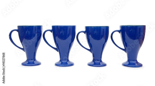 Slika na platnu Row of four blue long-stemmed coffee cups isolated