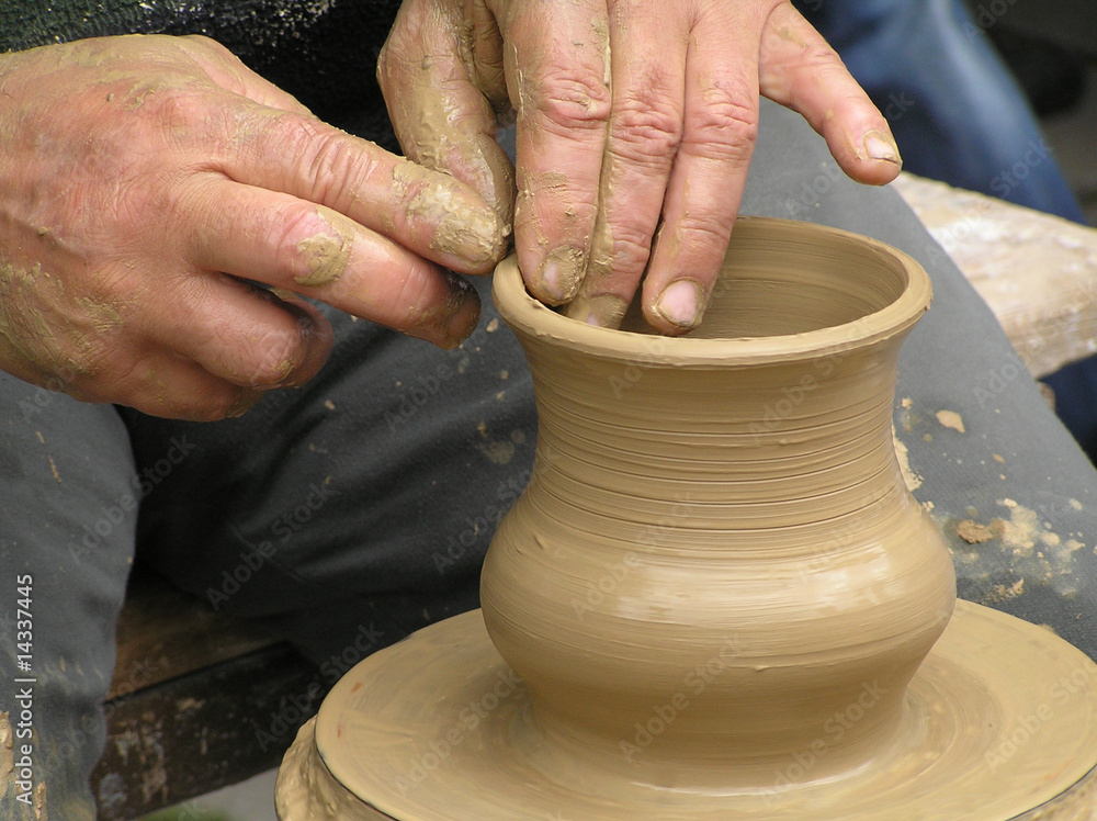 Potter working with clay bowl on potter's wheel