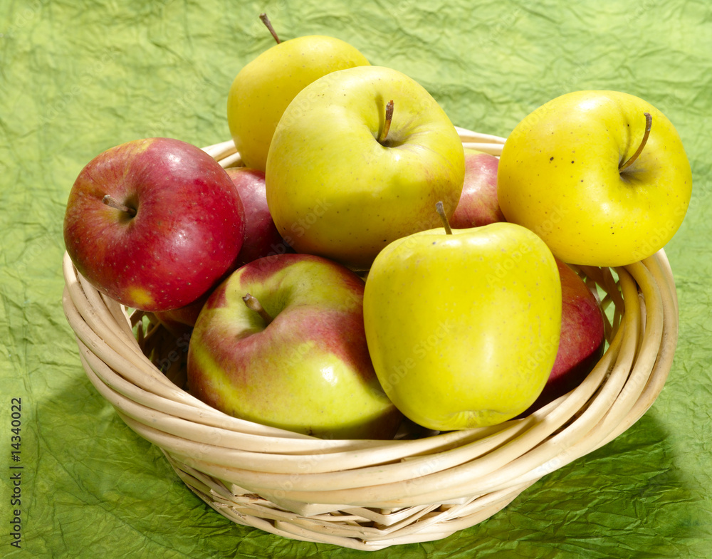 fresh juicy apples on green background in straw plate fresh juicy apples on green background in straw plate