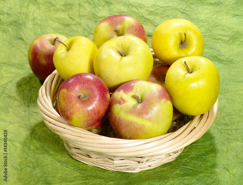 fresh juicy apples on green background in straw plate fresh juicy apples on green background in straw plate