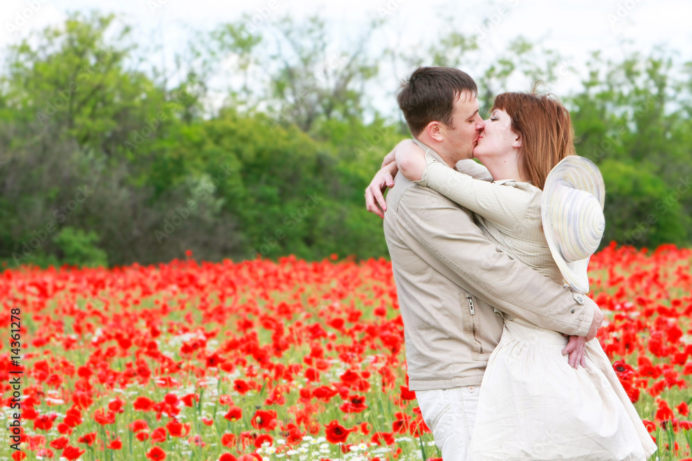 Naklejka premium kissing couple in red poppies field