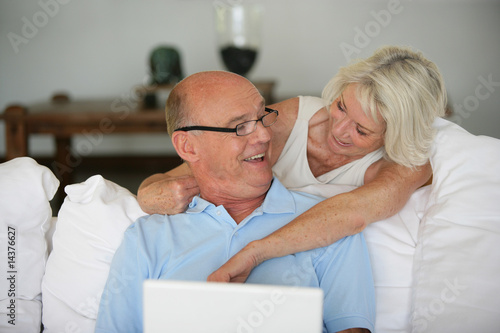 Couple de seniors se souriant devant un ordinateur portable