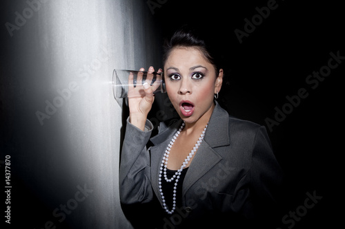 фотографія Pretty young Hispanic woman using glass to eavesdrop