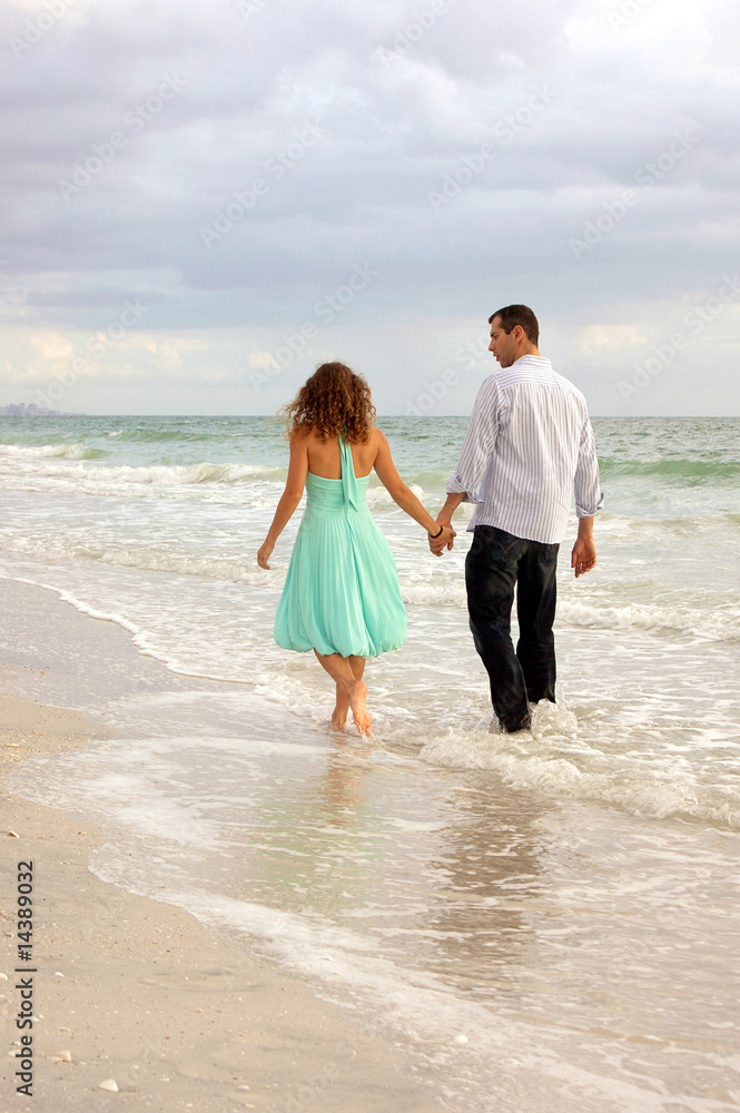 couple on beach walking away from viewer