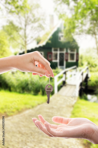 Handing over house key with a new home in the background